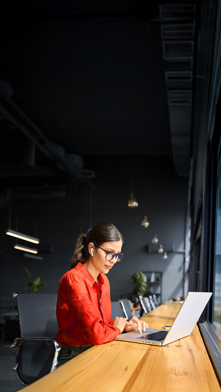 young business woman working on laptop computer at office desk with city view